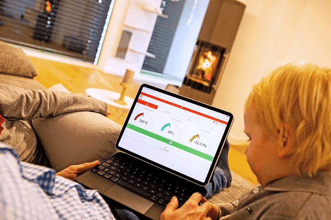 Person bedient Abbrandsteuerung eines Kaminofens über Tablet-Oberfläche mit Diagrammen in Wohnzimmer
