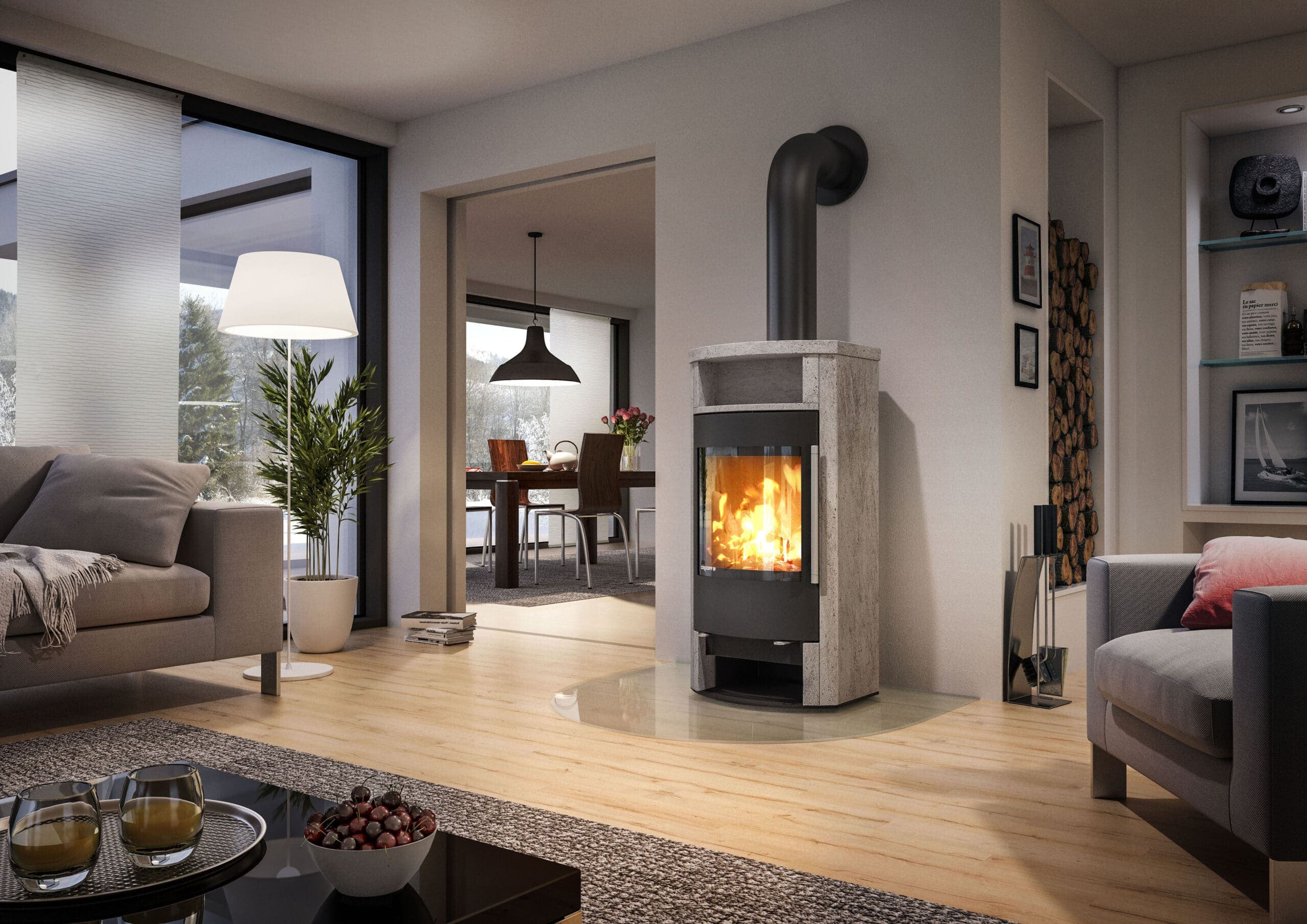 Kaminofen Arola mit Natursteineinfassung in grauem Betonlook, brennend in modernem Wohnzimmer mit Holzboden und Sesseln