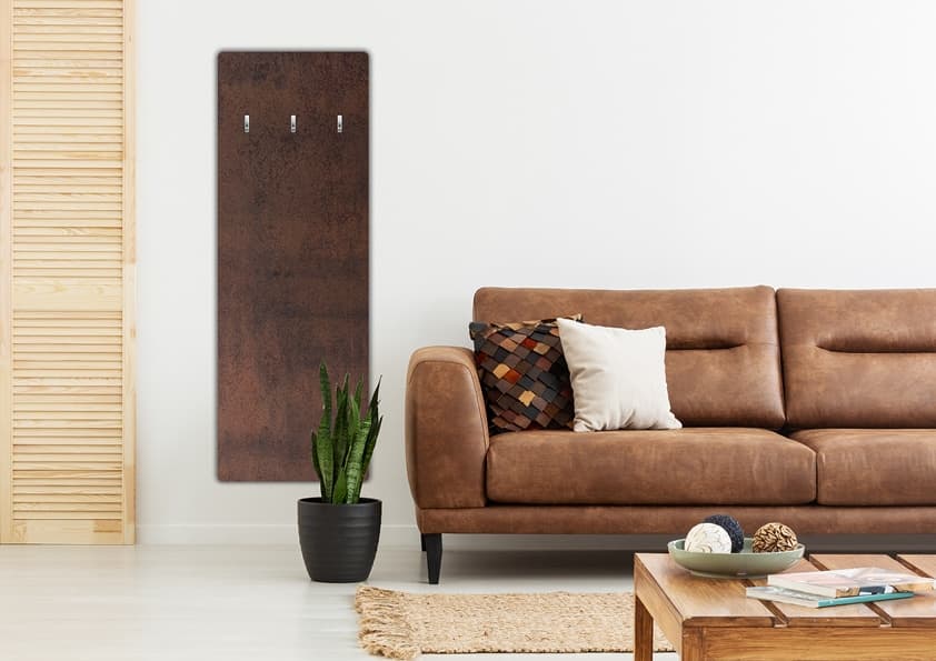 Moderner Kaminofen aus dunklem Naturstein an der Wand eines Wohnzimmers, davor ein braunes Ledersofa und Holzcouchtisch