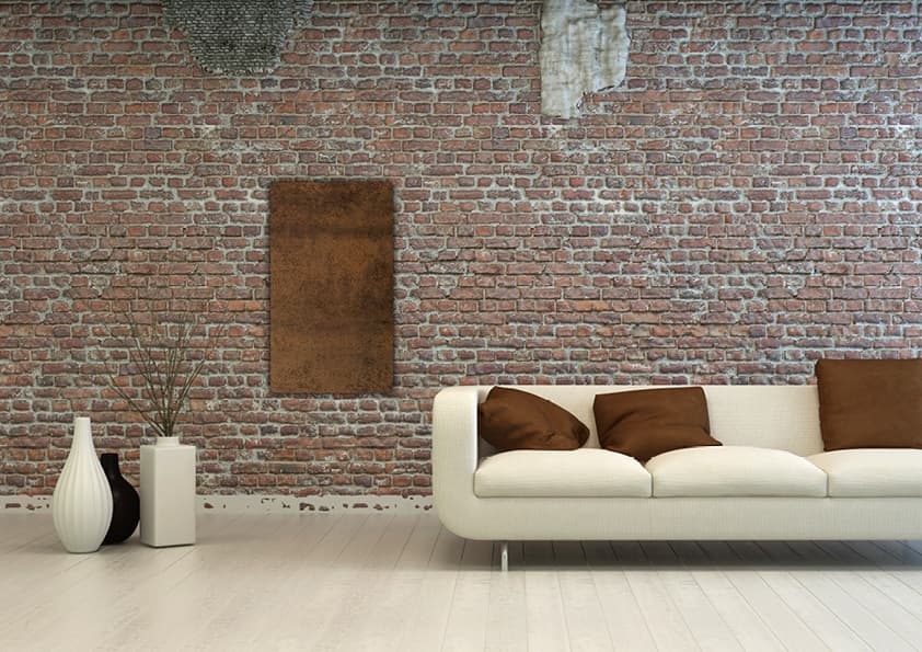 Moderne Wohnzimmerszenerie mit cremefarbenem Sofa, braunen Kissen und Backsteinwand mit rustikaler Patina