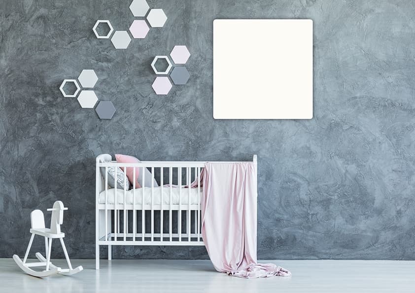 Kinderzimmer mit grauer Betonoptik-Wand, weißem Babybett, rosa Textilien und hexagonalen Wanddekoelementen