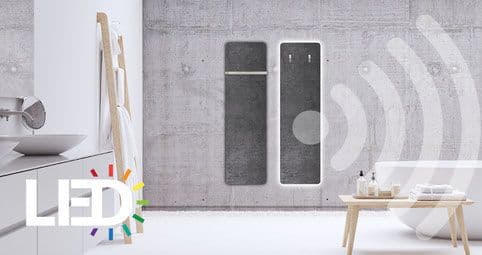Zwei dunkelgraue Speicheröfen mit integrierter LED-Beleuchtung in minimalistischem Wohnraum mit Holzakzenten und