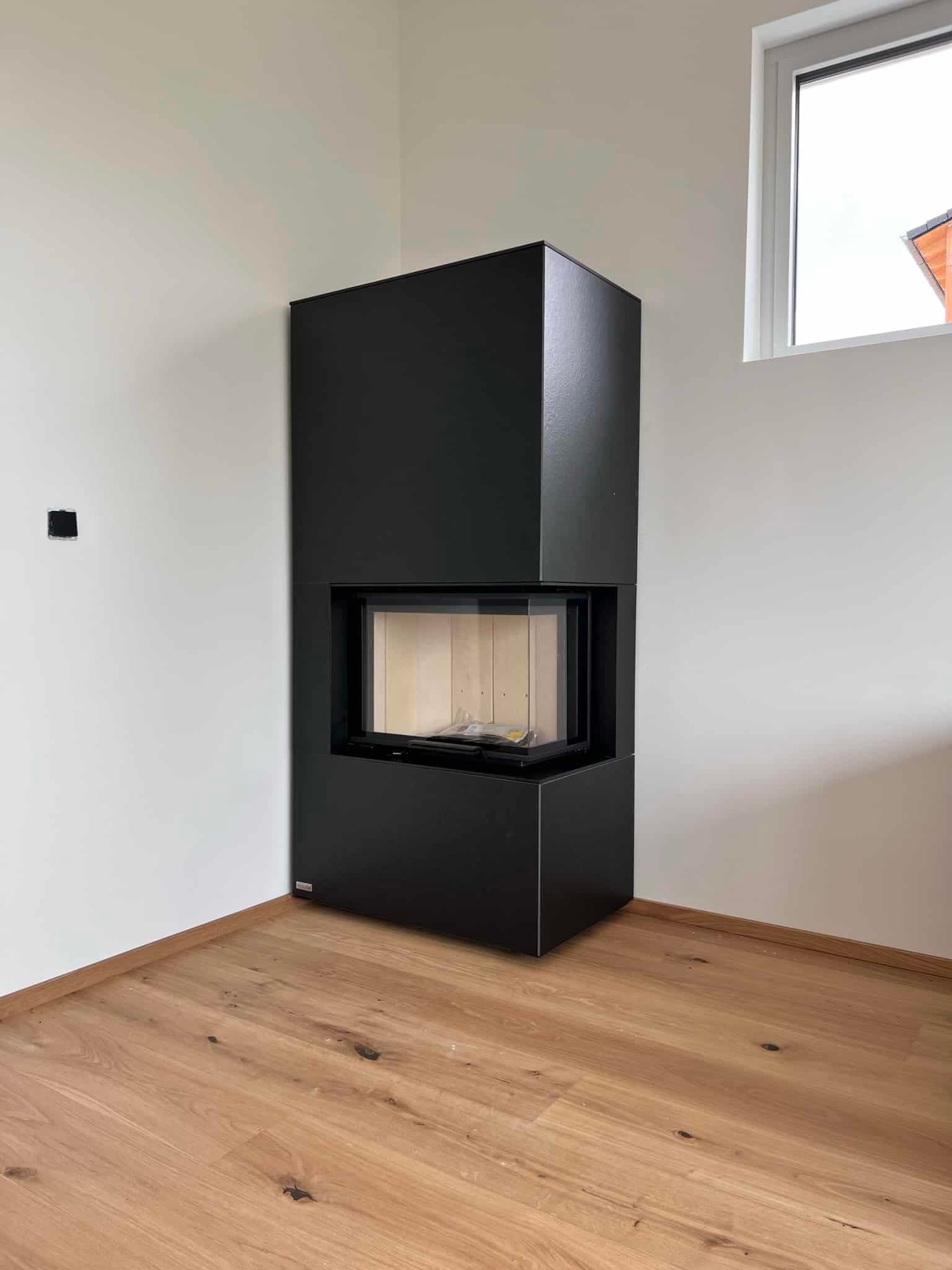 Moderner Kaminofen mit schwarzem Stahlgehäuse und rechteckiger Glasscheibe in minimalistischem Wohnraum