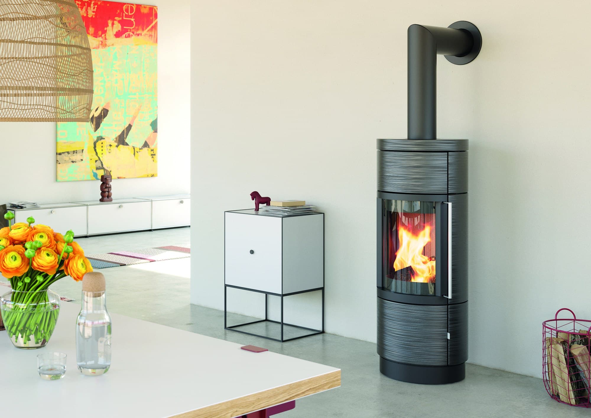 Hase Lima mit gebürsteter Keramik in Meteorit, dunkelgrau, an einer weißen Wand neben einem Sideboard, im Ofen brennt ein Feuer.
