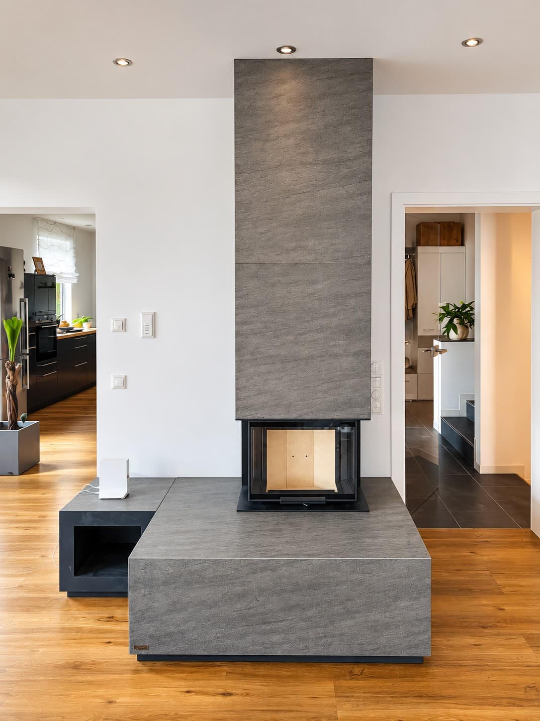 Blick von vorn auf den neocube P13: Feuerraum über Eck verglast, darüber die bis zur Decke geführte Keramik, rechts daneben die Glasplatte auf dem Eichenboden.