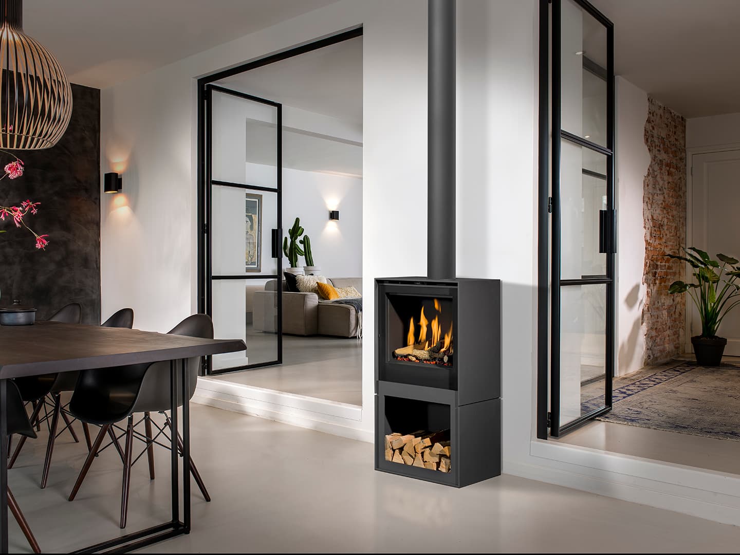 Gaskaminofen Barbas Box Gas 55 in anthrazitgrauem Gehäuse mit sichtbarem Holzlager, integriert in modernes Wohnzimmer mit Ess