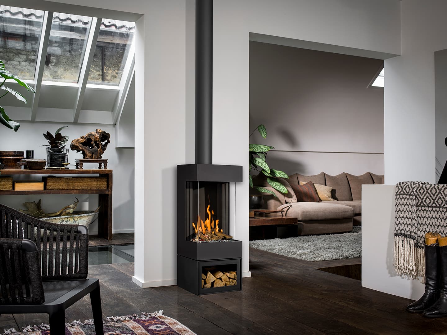 Barbas Bellfires Barbas Box Gas Panorama 45/59: Schwarzer Gaskamin mit Panorama-Sichtscheibe in modernem Wohnzimmer, Holzlagerung unten, offene Flamme sichtbar