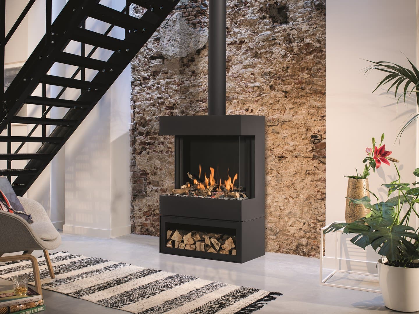 Gaskaminofen Barbas Box Gas Panorama 73/52 mit schwarzem Stahlrahmen in Loft-Interieur, Flammen sichtbar, Holzlagerung darunt