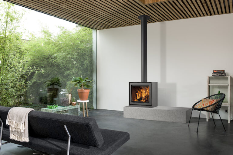 Kaminofen Barbas Bellfires BOX 67 auf Steinbank in modernem Wohnraum mit Glasfront